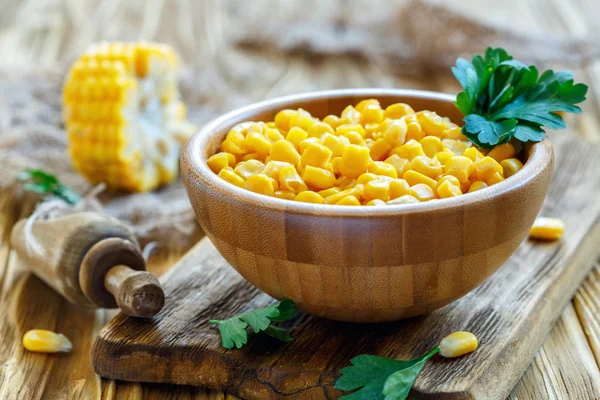 Canned corn and parsley in a wooden bowl.