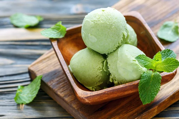 Balls of mint ice cream in a wooden bowl.