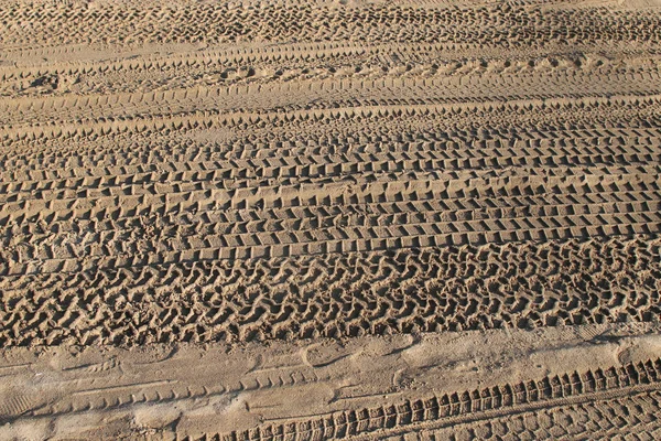 Les traces de pneus abstraites imprimées dans le sable — Photo