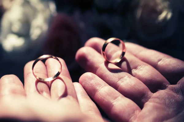 Χρυσά γαμήλια δαχτυλίδια σε έναν άνθρωπο με τα χέρια — Φωτογραφία Αρχείου