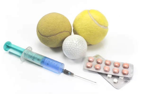 Теннис и мячик для гольфа со шприцем и таблетками на белом — стоковое фото
