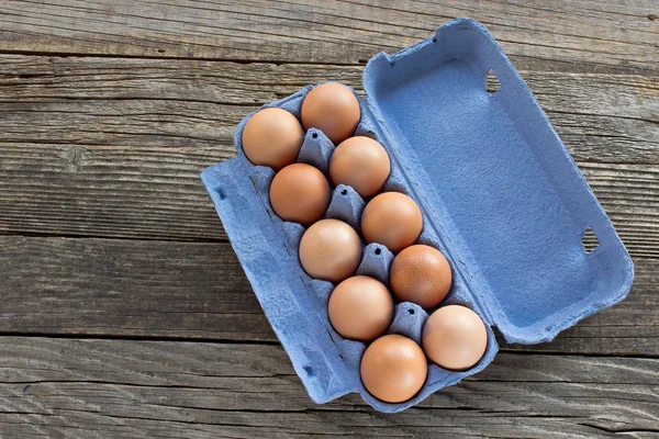 Eier in einer Pappverpackung auf Holzgrund — Stockfoto