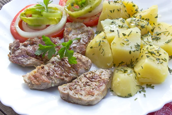 Carne de porco grelhada e legumes no prato — Fotografia de Stock