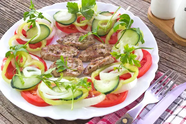 Carne de porco grelhada e salada de legumes em prato — Fotografia de Stock