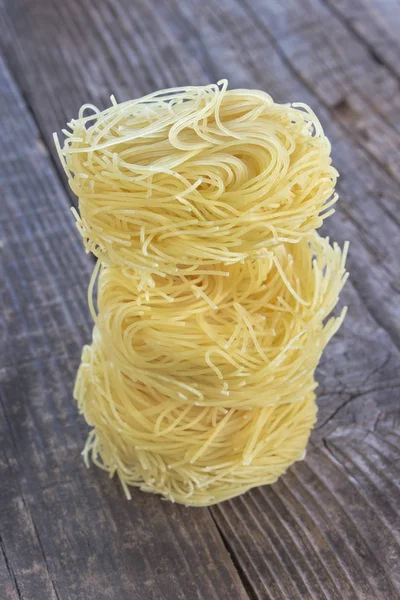 Vermicelli macarrão ninhos em fundo de madeira — Fotografia de Stock