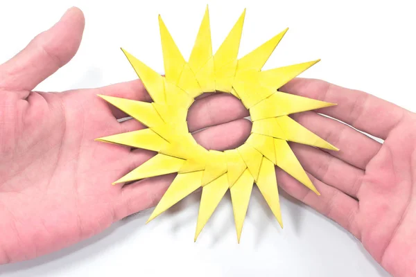 Origami geel papier zon in menselijke handen op wit — Stockfoto