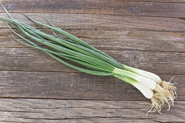 Young onion on wooden background — Stock Photo, Image