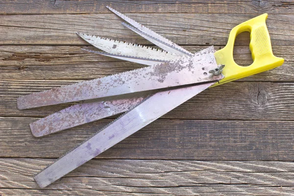 Handsaw with many changeable blades on wooden background — Stock Photo, Image