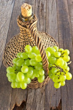 Eski hasır ile beyaz üzüm cam şişe ahşap masa üzerinde sarılı