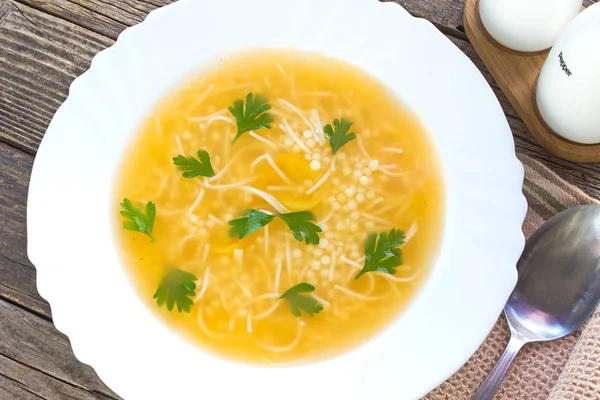 Klare Suppe im Teller auf altem Holztisch — Stockfoto