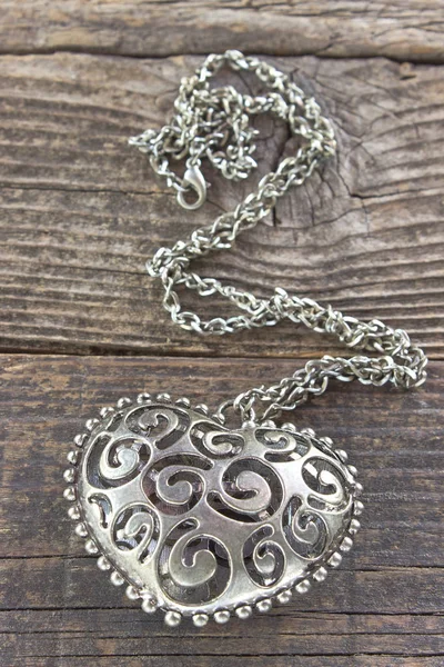 Collana in argento con cuore pendente su sfondo di legno — Foto Stock