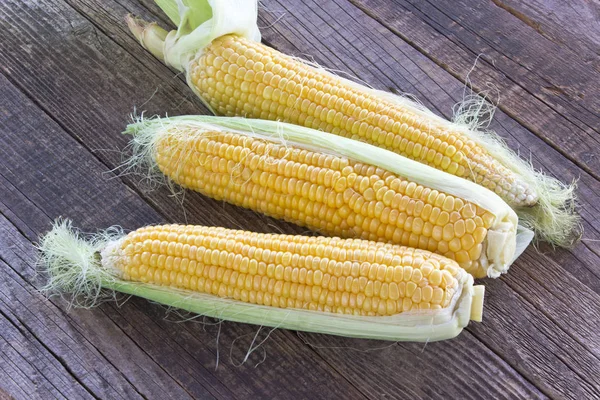 Ruwe maïskolven op houten achtergrond — Stockfoto