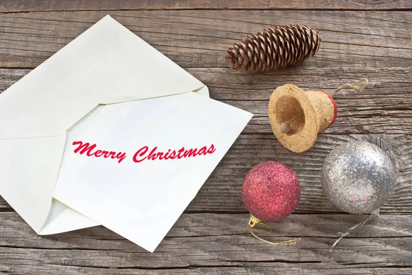 Веселого Рождества с письмом, шарами и колокольчиком на деревянном фоне — стоковое фото
