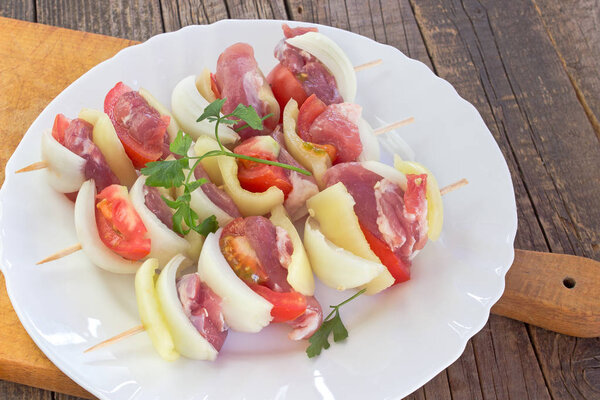 Raw meat for grill in plate with vegetables on cutting board