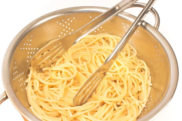 Свежеприготовленные спагетти в фильтре с щипцами на белом — стоковое фото