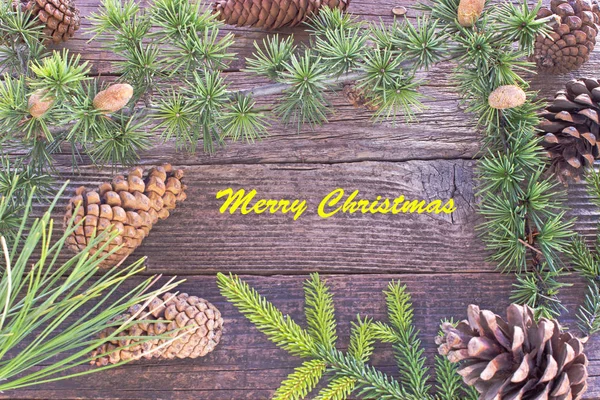 Merry Christmas with pine cones and needles on wooden background — Stock Photo, Image