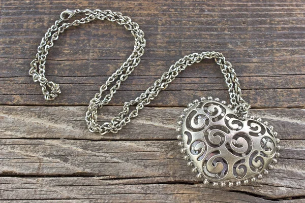 Silver necklace with heart pendant on wooden background — Stock Photo, Image