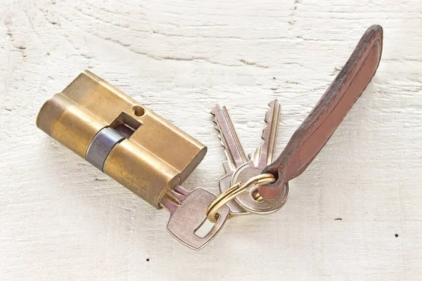Alter Messingpatronenzylinder mit Schlüsseln auf weißem Holzhintergrund — Stockfoto