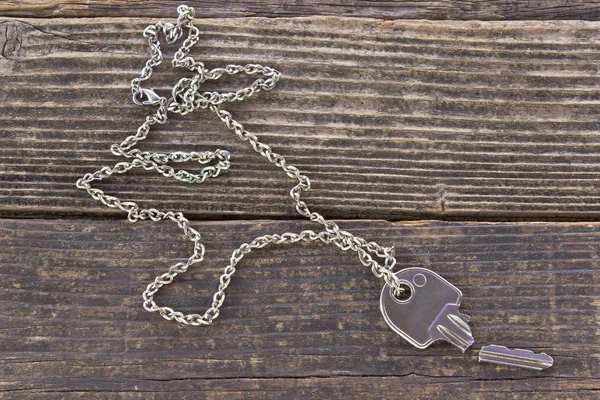 Broken house key on chain on wooden background