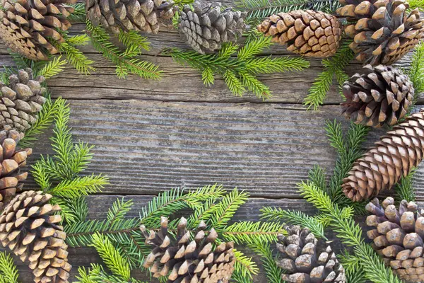 Feliz marco de Navidad con agujas de pino y conos en madera — Foto de Stock
