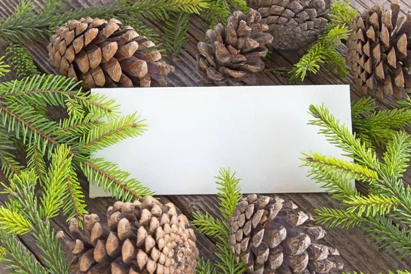 Merry Christmas card with pine tree needles and cones on wooden — Stock Photo, Image