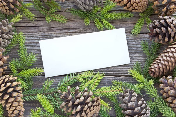 Merry Christmas card with pine tree needles and cones on wooden — Stock Photo, Image