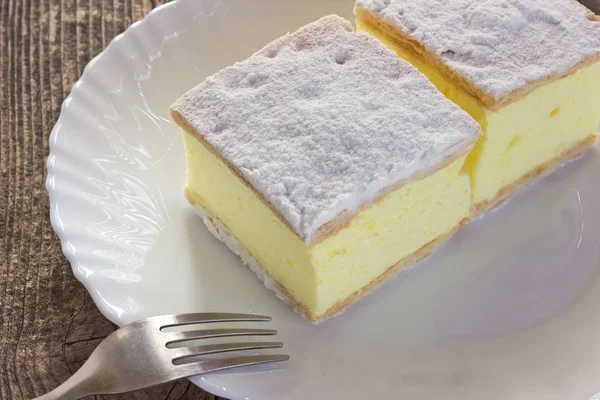 Torta de creme com camadas de massa folhada em placa na mesa de madeira — Fotografia de Stock