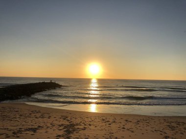 Portekiz 'in Costa da Caparica plajında gün batımı