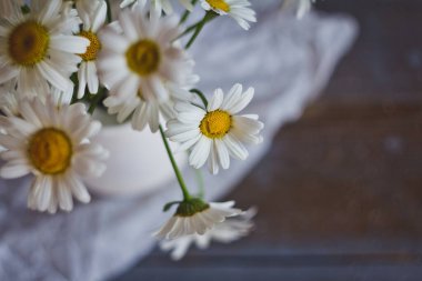 Tahta bir masadaki vazoda bir buket papatya.