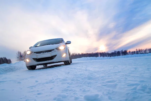 Білий автомобіль взимку поля на дорозі. Стокове Фото