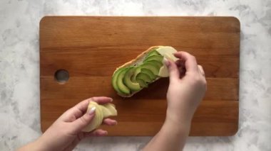 Bir kadın avokado ve armutla bruschetta hazırlar.