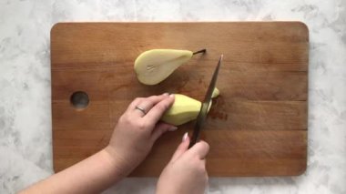 Bir kadın yemek tarifi için armudu dilimliyor.