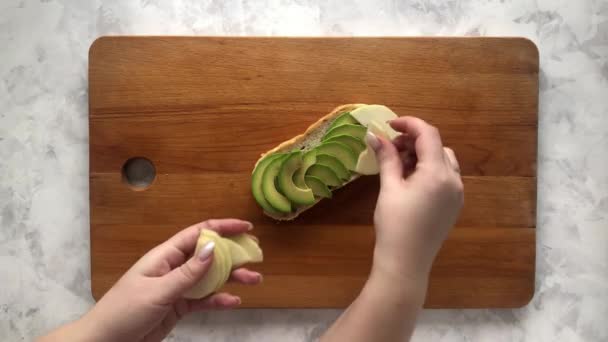 Une femme prépare une bruschetta à l'avocat et à la poire — Video