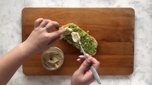 Putting hummus on avocado bruschetta — Stock Video