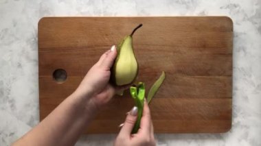 Bir kadın sandviç yapmak için armudu sebze soyacağı ile temizler.