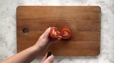 Bir kadın ahşap bir tahtada domates doğruyor.