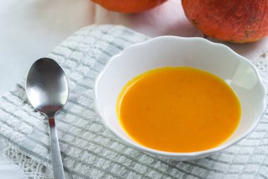 Beyaz masa örtüsü üzerinde sonbahar balkabağı çorbası.