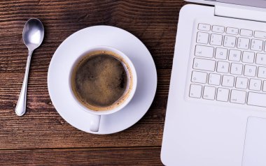 Beyaz fincan kahve kaşık ve doğal ahşap masa üstünde defter ile.