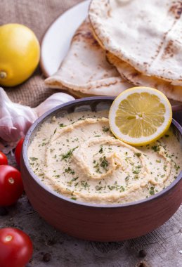 Humus limon, domates ve chapation doğal ahşap Masası ile ev yapımı kase.