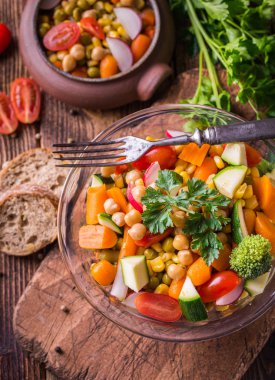 Doğal rustik masa üzerinde cam kase sebze salatası.