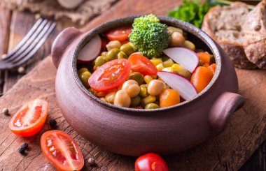 Doğal ahşap masa üzerinde ev hazırlanmış kase sebze salatası.