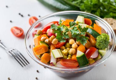 Brokoli ve domates beyaz masada cam kase sebze salatası.