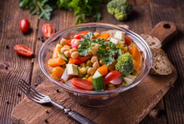 Brokoli ve koyu ahşap masa üzerinde domates cam kase sebze salatası.