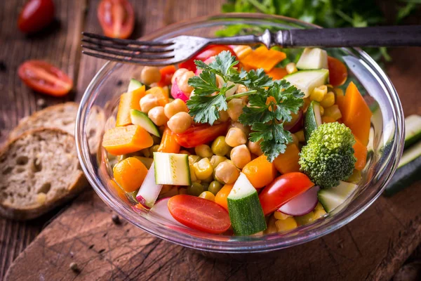 Ensalada de verduras en tazón de vidrio con brócoli y tomates en la oscuridad — Foto de Stock