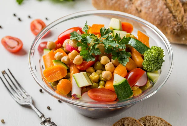 Ensalada de verduras en tazón de vidrio con brócoli y tomates sobre mesa blanca . — Foto de Stock