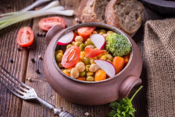 Salade de légumes dans un bol artisanal avec tomates sur onglet en bois — Photo