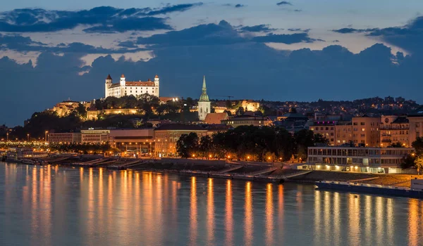 Bratislavský hrad v noci s odrazem světla na břehu řeky dunaj. — Stock fotografie
