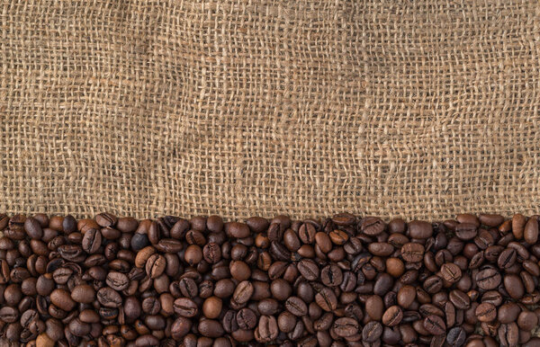 Mixture of different kinds of coffee beans on jute background.