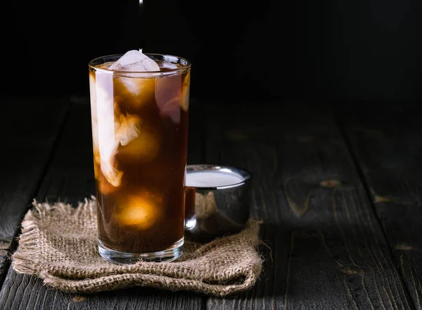 Холодный кофе в высоком стакане на фоне джута . — стоковое фото