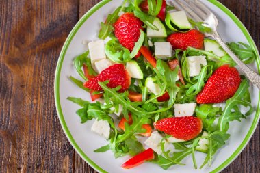 Doğal rustik masa üzerinde beyaz tabakta sebze taze çilek salatası.